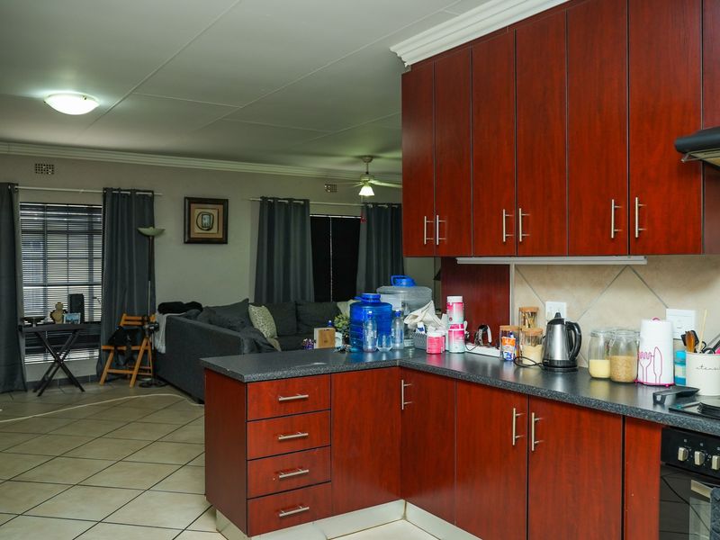 Open-plan kitchen and living area featuring dark wood cabinetry, laminate countertops, built-in oven, and tiled flooring throughout the space.