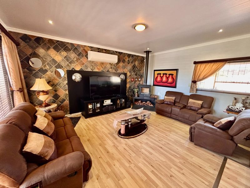 Spacious living room featuring a wood-burning fireplace, split-system air conditioning, and a distinctive stone-tiled feature wall with light wood-look flooring.