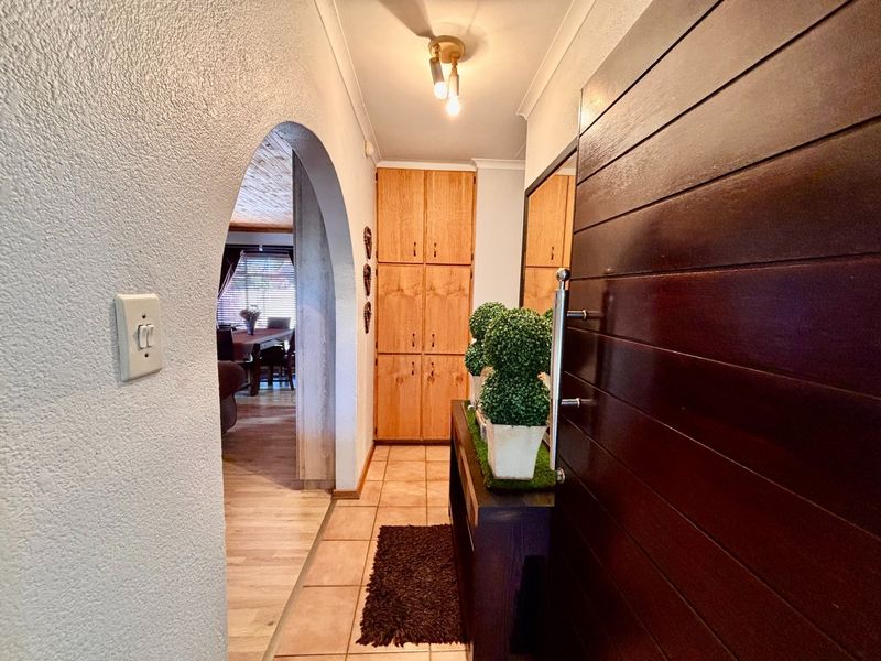 Welcoming entrance hall featuring tiled flooring, built-in storage cabinetry, and a distinctive arched doorway leading into the main living area.