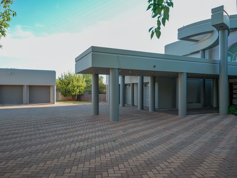 Spacious paved driveway leading to a modern residence featuring a covered porte-cochere and multiple garage bays.