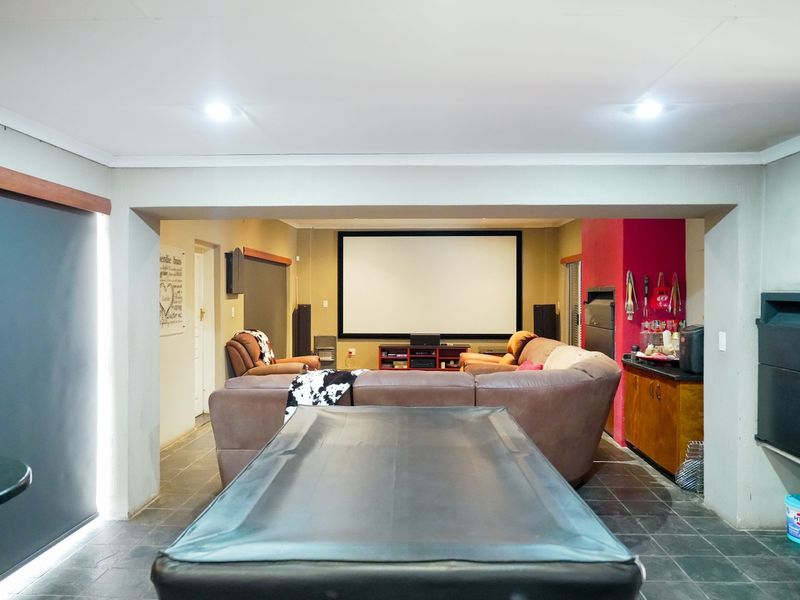 A spacious entertainment area featuring a dedicated cinema screen, built-in fireplace, and tiled flooring, designed for comfortable home viewing and leisure.