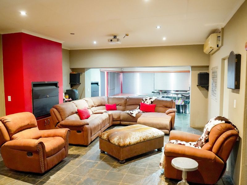 Spacious living area featuring stone tile flooring, a built-in fireplace, recessed lighting, and a wall-mounted air conditioning unit.