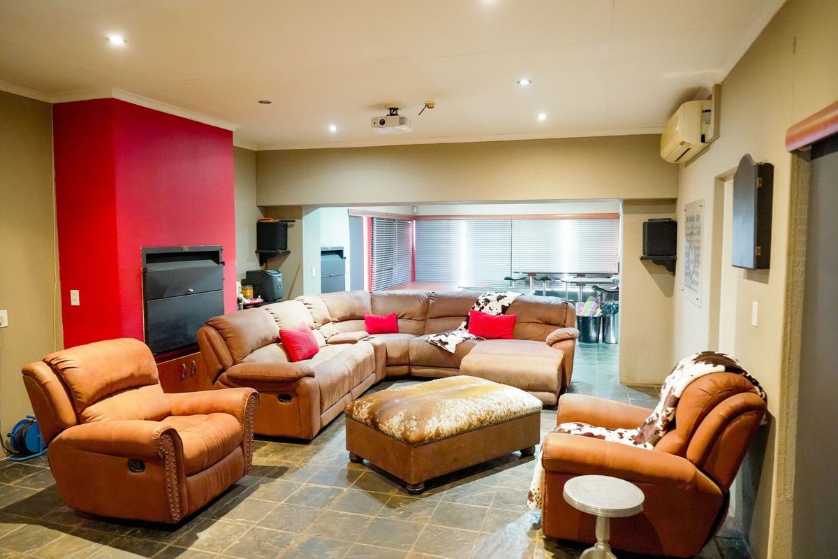 Spacious living area featuring stone tile flooring, a built-in fireplace, recessed lighting, and a wall-mounted air conditioning unit.