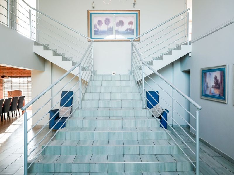 A grand double staircase featuring tiled steps and modern metal balustrades, serving as a central architectural feature in the entrance hall.
