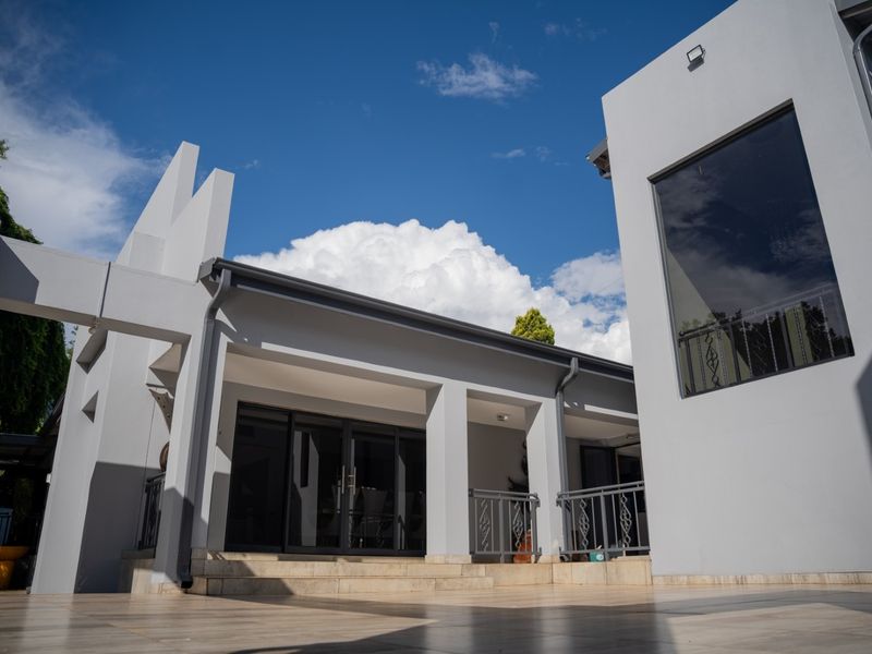 A modern rear exterior view featuring a spacious tiled patio, clean architectural lines, and large glass sliding doors leading into the home.