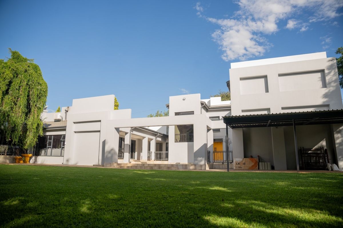 Rear view of a modern house featuring a spacious lawn, covered patio area, and clean architectural lines.