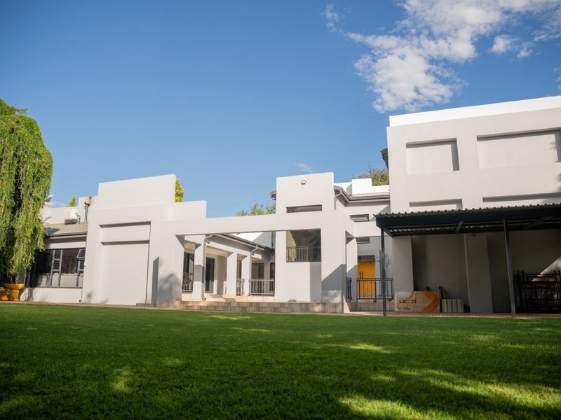 Rear view of a modern house featuring a spacious lawn, covered patio area, and clean architectural lines.