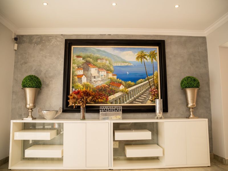 A well-maintained living area featuring a textured grey feature wall, recessed downlighting, and decorative coving, creating a modern and polished aesthetic.