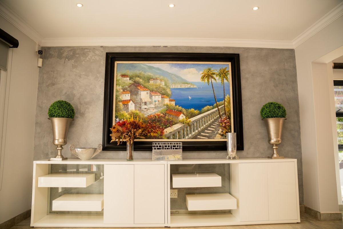 A well-maintained living area featuring a textured grey feature wall, recessed downlighting, and decorative coving, creating a modern and polished aesthetic.