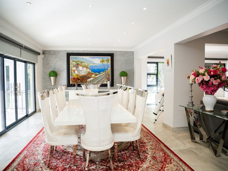 A bright and elegant dining room featuring tiled flooring, recessed downlighting, and large sliding glass doors that provide ample natural light.