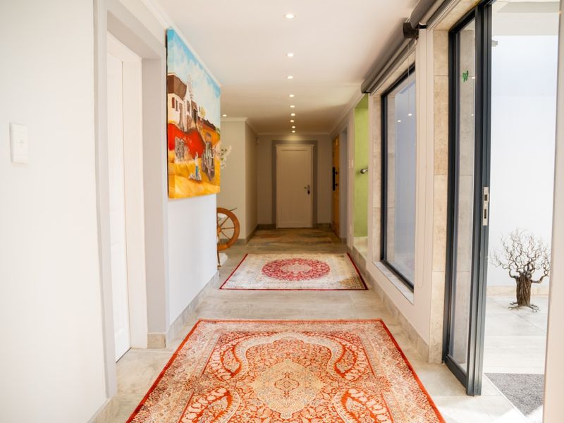 A bright and spacious hallway featuring tiled flooring, recessed downlighting, and large sliding glass doors providing access to an outdoor area.