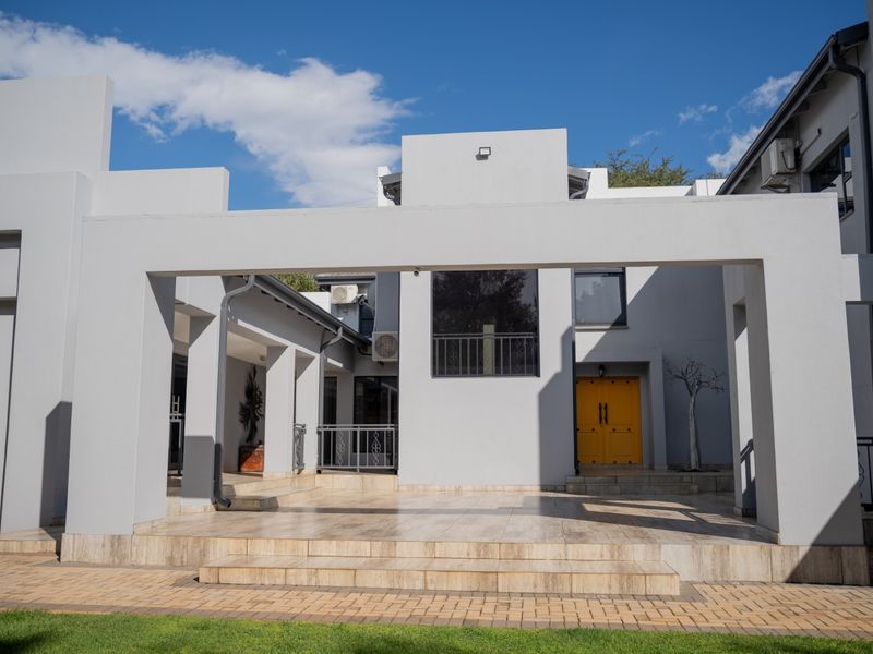 Modern architectural front facade featuring a covered tiled patio, striking yellow double entrance doors, and clean grey exterior finishes.