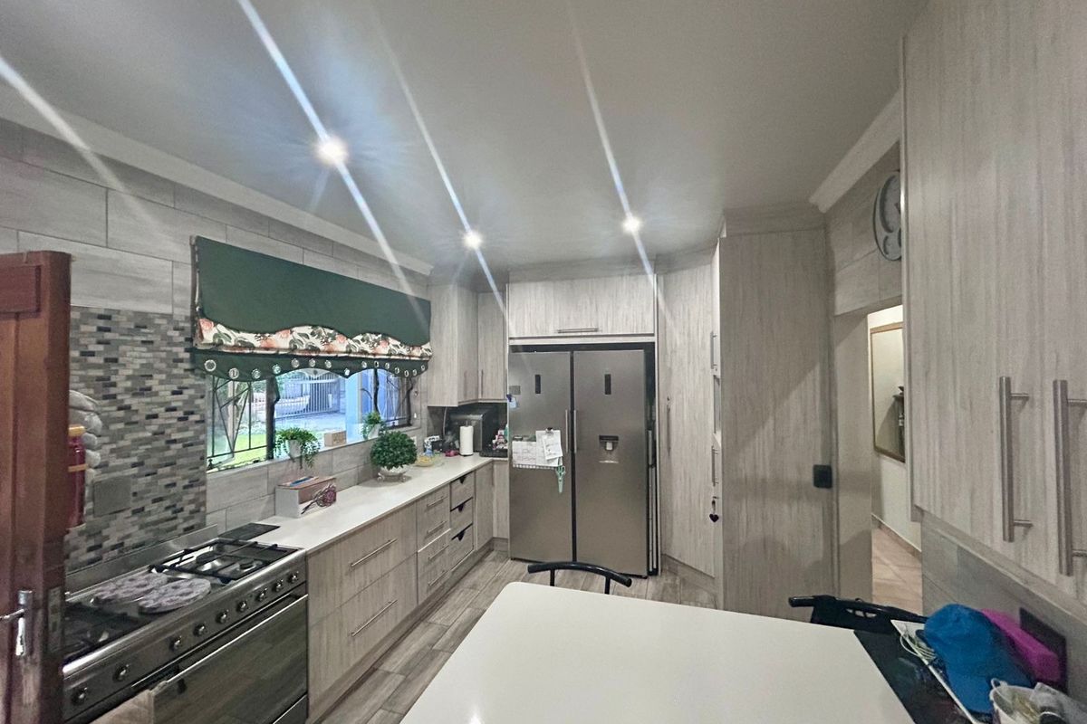Modern kitchen featuring light wood-grain cabinetry, stone countertops, a mosaic tile backsplash, and a stainless steel gas stove with an integrated extractor.