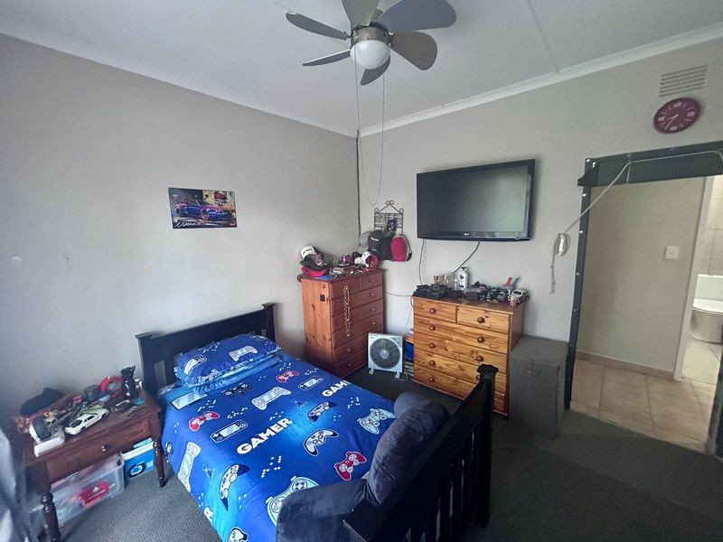 A standard bedroom featuring a ceiling fan and neutral wall finishes, with direct access to an adjoining bathroom.