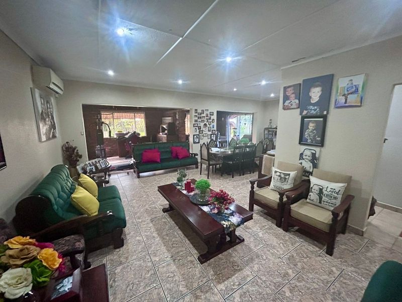 Spacious open-plan living and dining area featuring tiled flooring, recessed lighting, and a split-system air conditioner, leading to an adjoining covered patio space.
