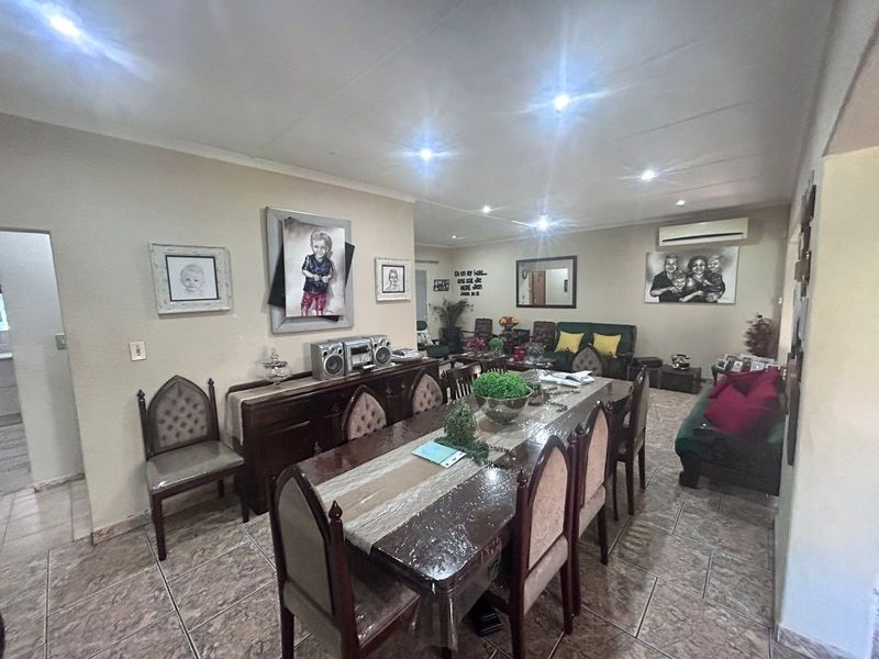 Spacious open-plan living and dining area featuring ceramic floor tiles, recessed downlighting, and a wall-mounted air conditioning unit.