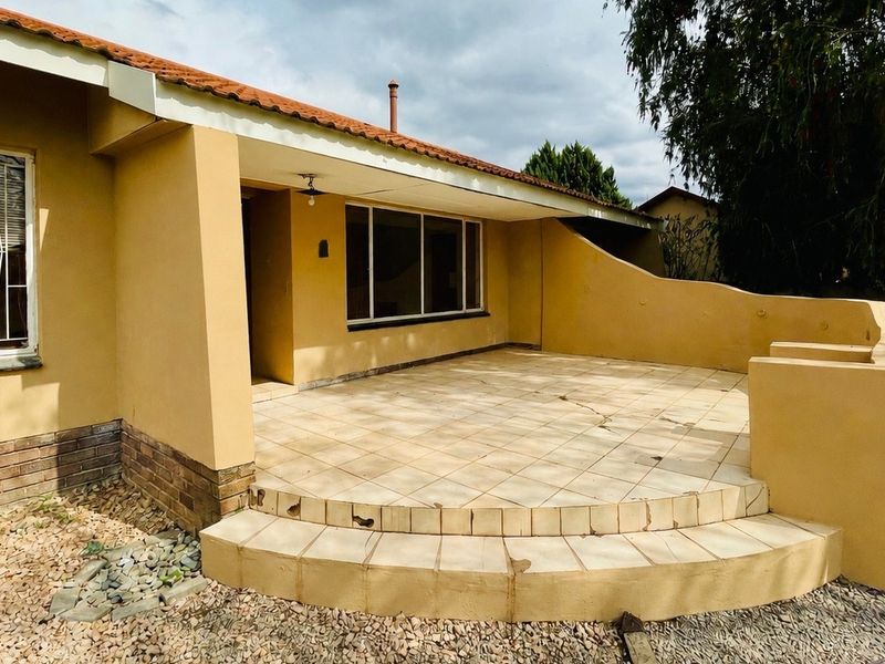 A covered outdoor patio area featuring tiled flooring, a curved masonry wall, and direct access to the home's exterior.