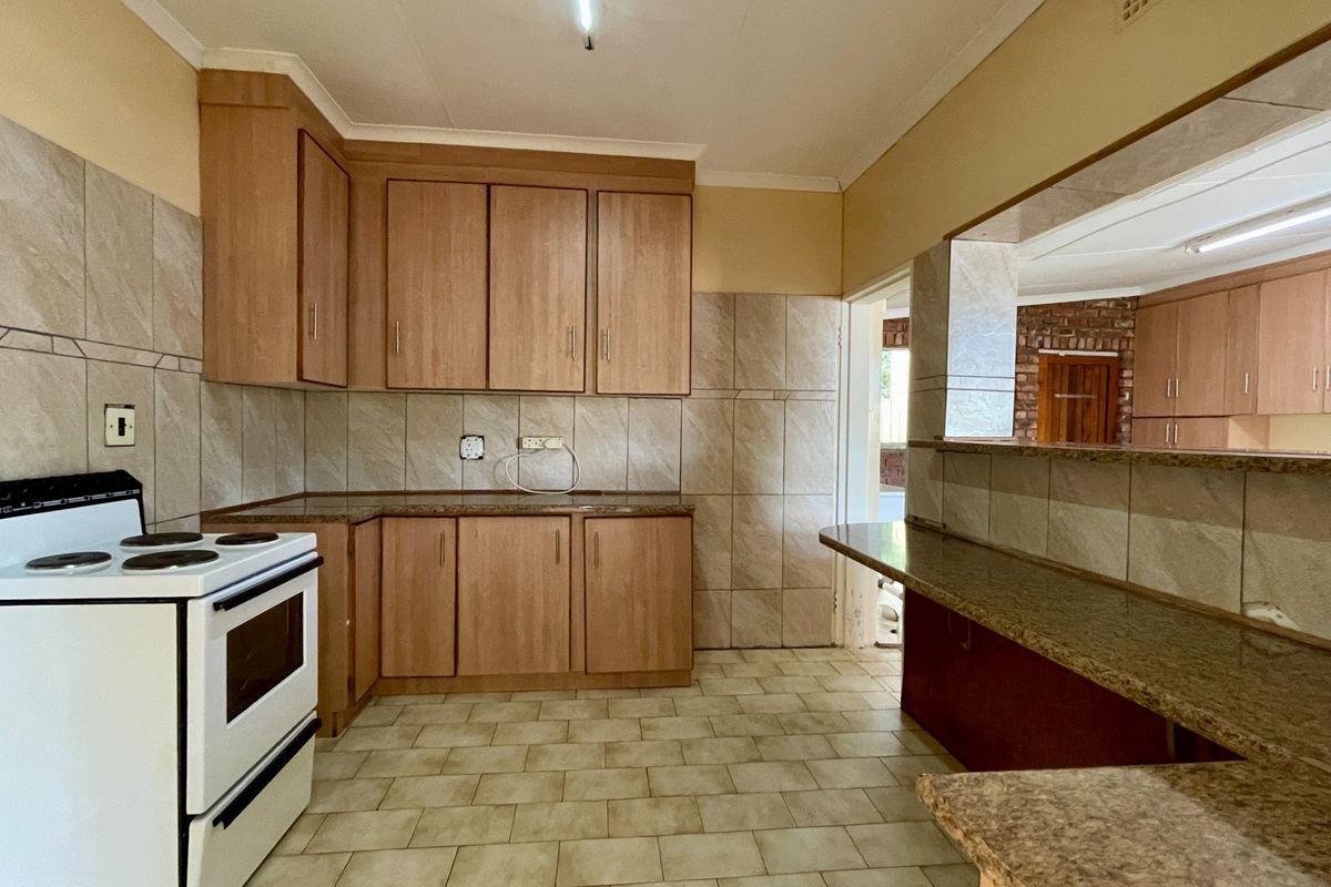 A functional kitchen featuring laminate cabinetry, granite countertops, tiled splashbacks, and a breakfast bar, offering a clean and practical layout for daily use.