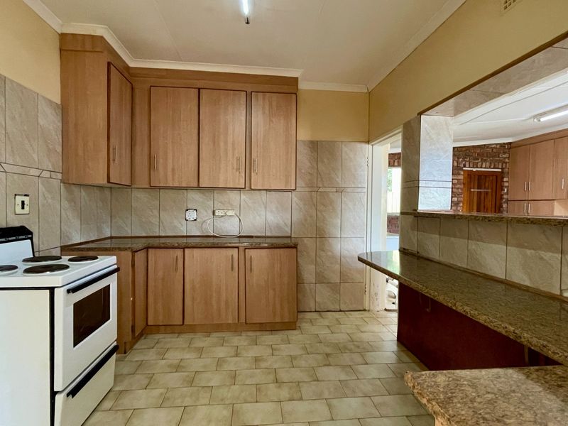 A functional kitchen featuring laminate cabinetry, granite countertops, tiled splashbacks, and a breakfast bar, offering a clean and practical layout for daily use.