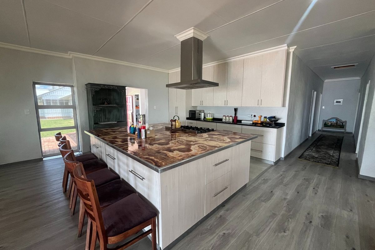 Modern open-plan kitchen featuring a large central island with a unique stone countertop, built-in cabinetry, and a stainless steel extractor fan.