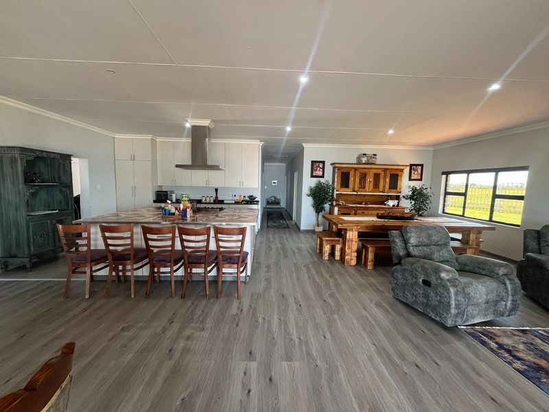 Spacious open-plan living area featuring a modern kitchen with a large island, recessed lighting, and durable laminate flooring throughout.
