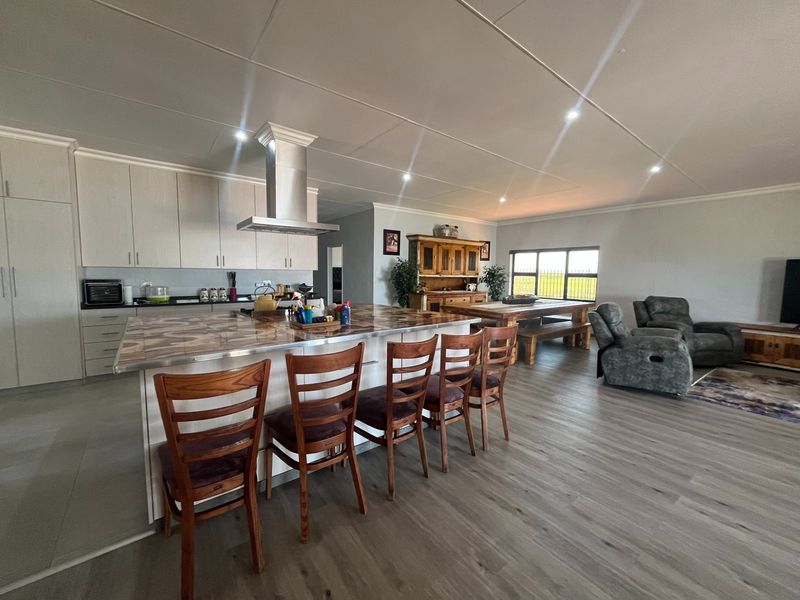 Spacious open-plan living area featuring a modern kitchen with a large island, integrated extractor fan, and durable laminate flooring throughout.