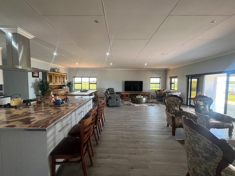 Spacious open-plan living area featuring a modern kitchen with a large island, laminate flooring, and seamless access to the outdoor patio through sliding doors.