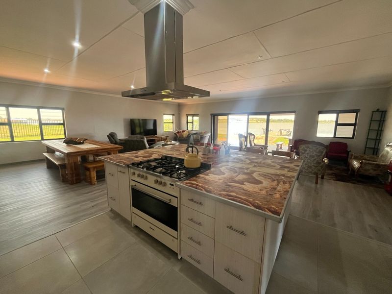 Spacious open-plan living area featuring a central kitchen island with gas hob, integrated oven, and large sliding doors opening to a scenic outdoor view.