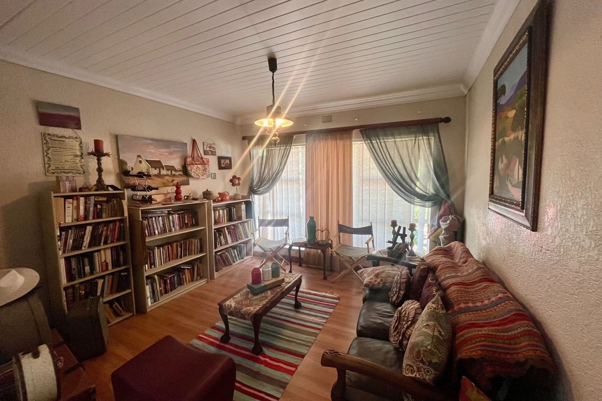A cozy living room featuring laminate flooring, a tongue and groove ceiling, and natural light through large windows.