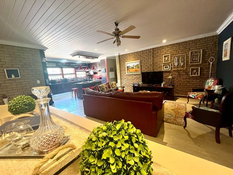 Spacious open-plan living area featuring an exposed brick feature wall, tongue and groove ceiling, and a functional kitchen with a central island.