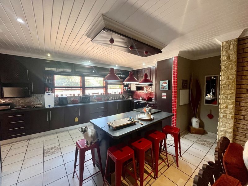Spacious kitchen featuring dark cabinetry, a central island, tiled flooring, and a distinctive stone feature wall, offering a functional and well-defined cooking space.