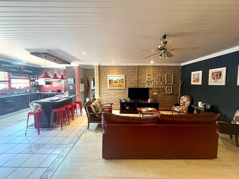 Spacious open-plan living area featuring a modern kitchen with island seating, exposed brick feature wall, and tiled flooring throughout.