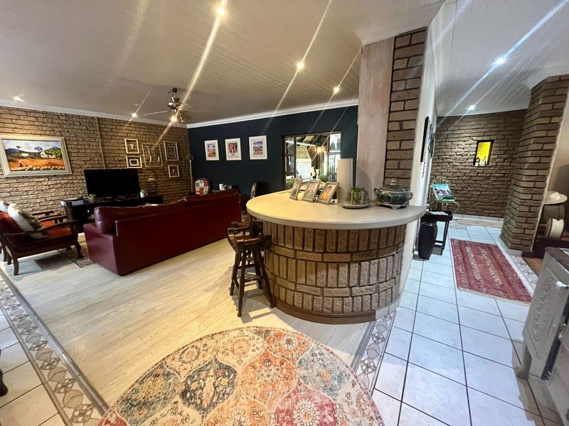 Open plan living area featuring exposed brick walls, a built-in brick breakfast bar, and a combination of tiled and laminate flooring.