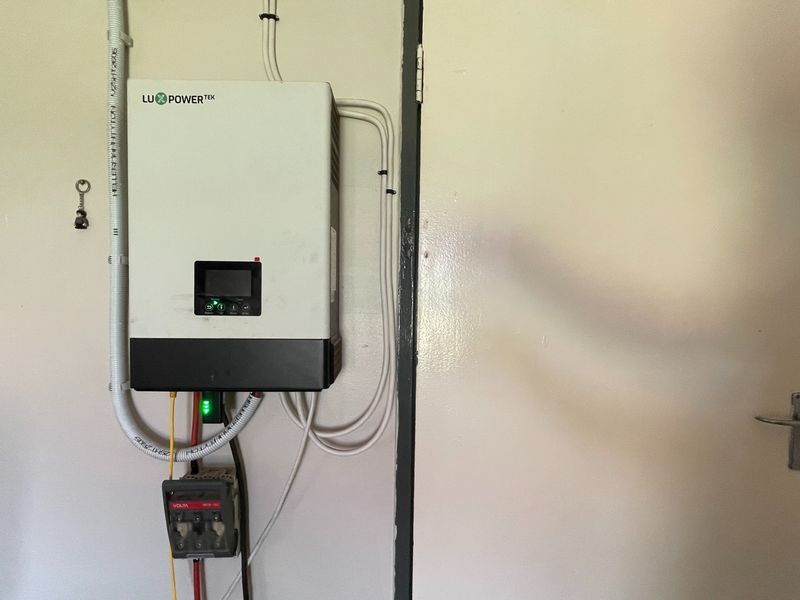 A wall-mounted solar power inverter and electrical isolator switch installed in a utility area.
