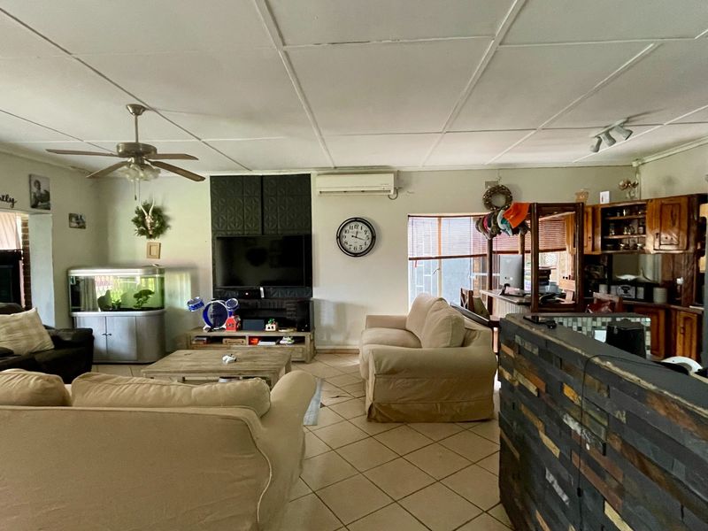 Open-plan living and kitchen area featuring tiled flooring, a ceiling fan, split-system air conditioning, and built-in cabinetry.