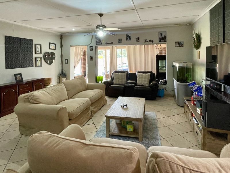 Spacious living room featuring tiled flooring, a ceiling fan, and direct access to the outdoor area through a sliding glass door.