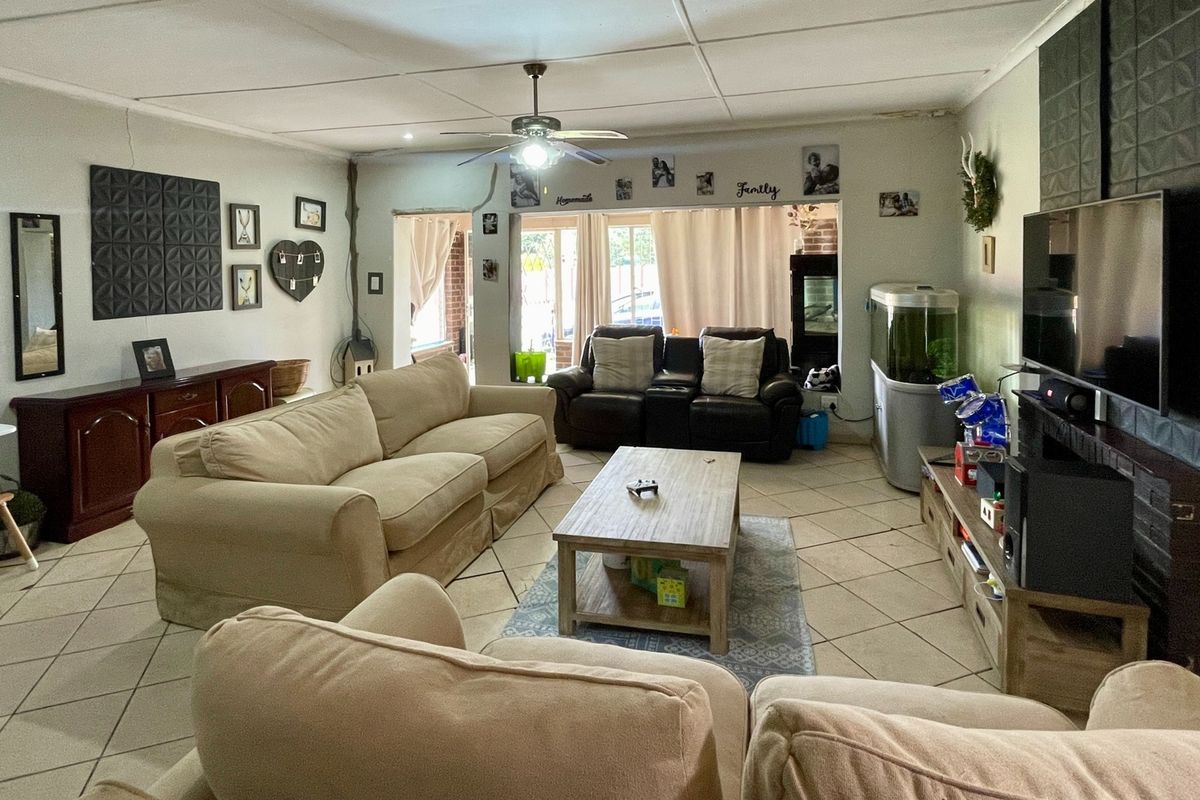 Spacious living room featuring tiled flooring, a ceiling fan, and direct access to the outdoor area through a sliding glass door.