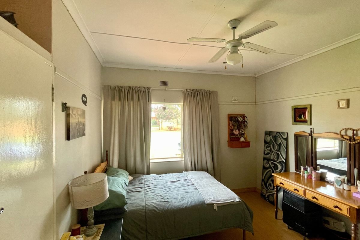 A standard bedroom featuring a ceiling fan, built-in cupboard storage, and a picture rail, providing a functional and well-lit sleeping space.