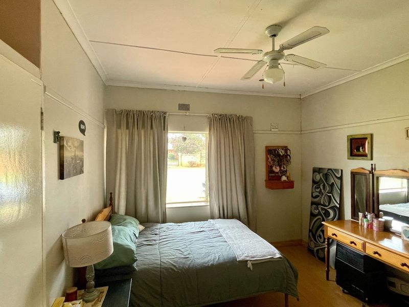 A standard bedroom featuring a ceiling fan, built-in cupboard storage, and a picture rail, providing a functional and well-lit sleeping space.