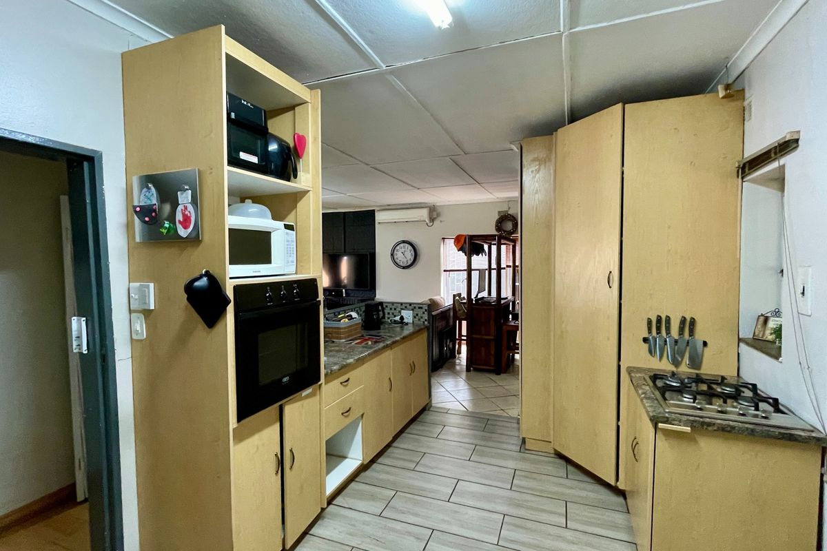 A functional kitchen featuring light wood-tone cabinetry, laminate countertops, a built-in oven, and a gas hob, with tiled flooring throughout.