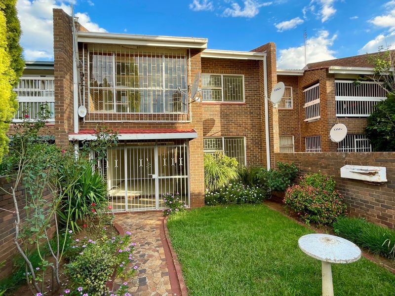 Rear view of a face brick townhouse featuring a private garden, stone pathway, and security-fitted windows and doors.
