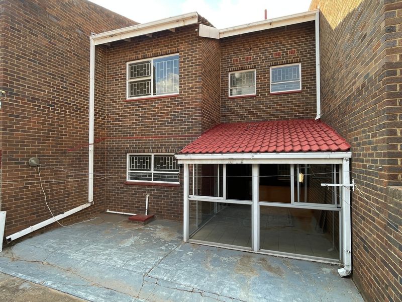 Rear exterior view of the townhouse featuring a brick facade, a small enclosed patio area, and a paved courtyard space.