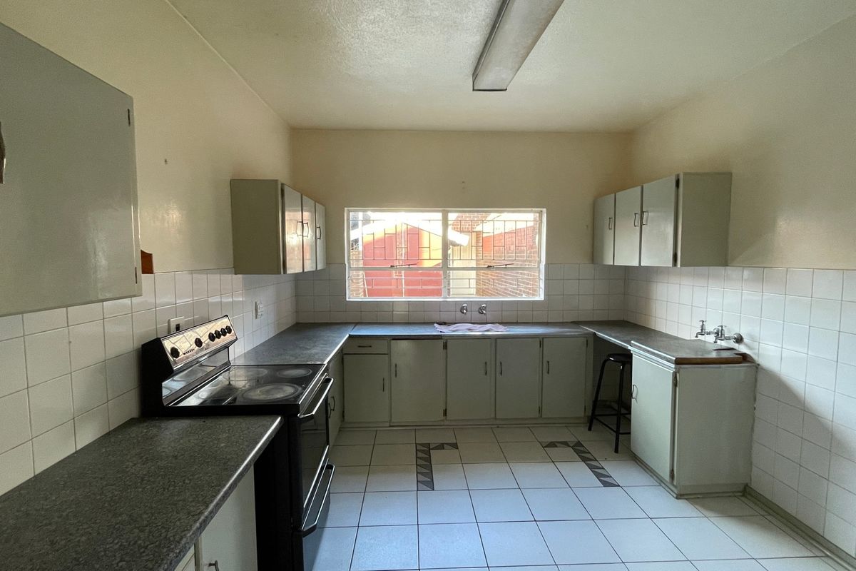A functional kitchen featuring built-in cabinetry, laminate countertops, tiled backsplash, and a freestanding electric stove, offering a blank canvas for renovation.