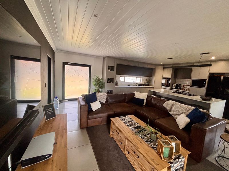 Spacious open-plan living area featuring a modern kitchen with a central island, built-in appliances, and stylish tongue and groove ceiling finishes.