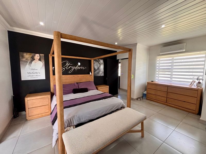 Spacious bedroom featuring tiled flooring, a tongue and groove ceiling with recessed lighting, and a wall-mounted air conditioning unit.