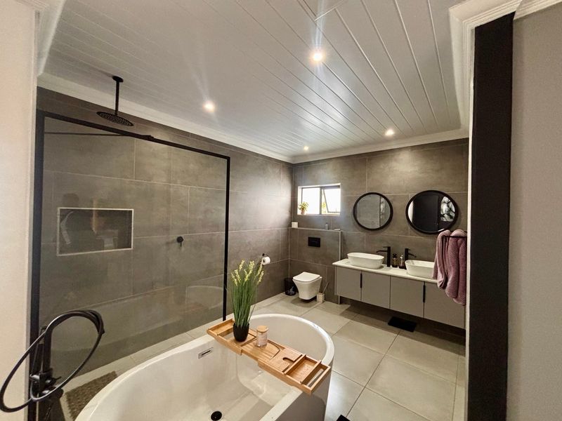 Modern, well-appointed bathroom featuring a freestanding bathtub, spacious walk-in shower, double vanity, and contemporary wall-mounted toilet with high-quality finishes.