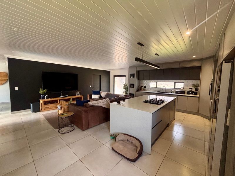 Spacious open-plan living area featuring a modern kitchen with a central island, gas hob, and sleek cabinetry, seamlessly flowing into the lounge space.