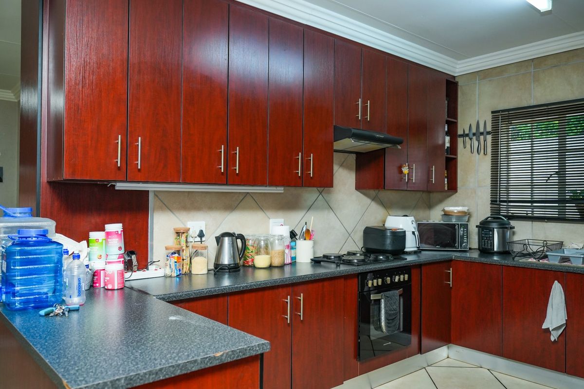 A functional kitchen featuring dark wood-finish cabinetry, laminate countertops, a gas hob, and a built-in oven with a tiled backsplash.