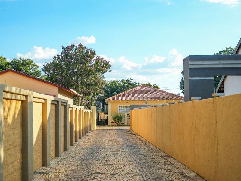 A paved driveway leading towards the front entrance of the property, enclosed by solid perimeter boundary walls.