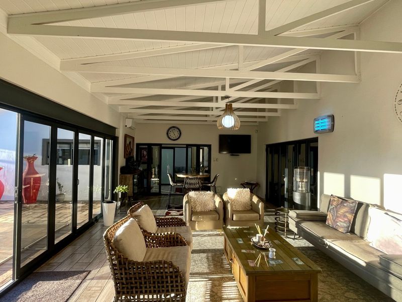 Spacious covered patio featuring exposed white timber trusses, large sliding glass doors providing seamless indoor-outdoor flow, and durable tiled flooring.